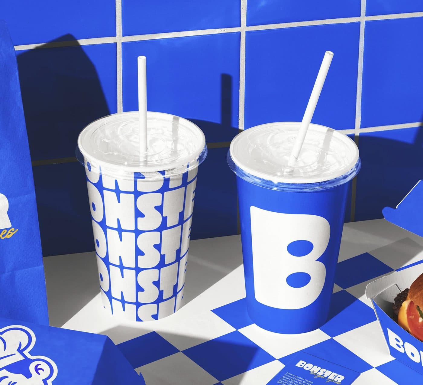 Two printed cold drink cups with lids and straws