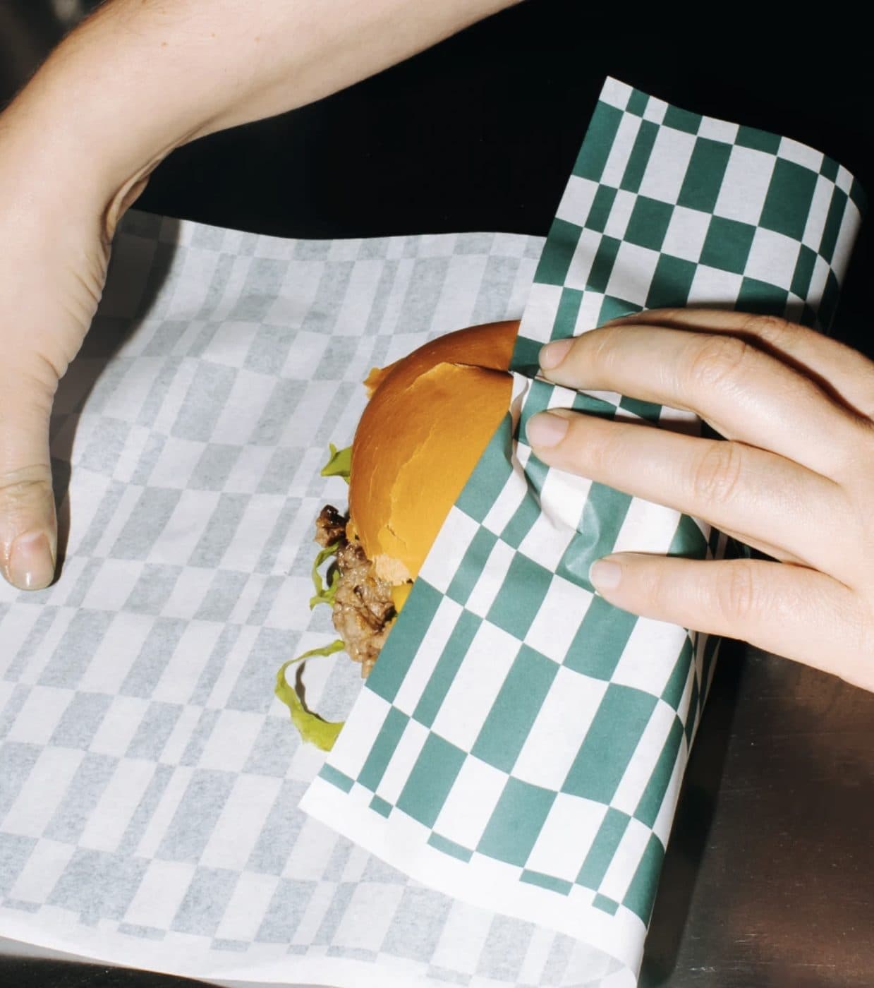 Burger being wrapped in printed greaseproof paper